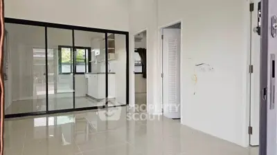Modern open-plan living area with glass partition and sleek kitchen design