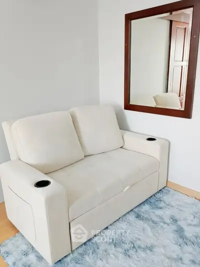 Cozy living room with plush white sofa and elegant wall mirror on soft blue rug.