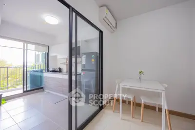Modern kitchen with open layout and balcony view, featuring sleek appliances and minimalist dining area.