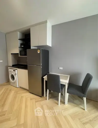 Modern kitchen with sleek appliances and cozy dining area in stylish apartment.