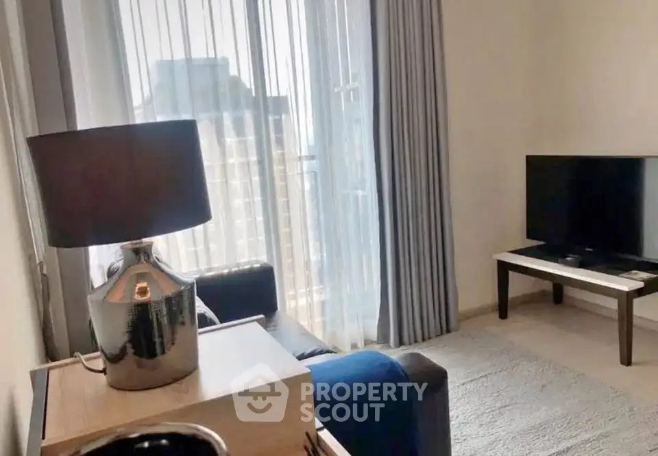 Modern living room with sleek furniture and large window offering city views.