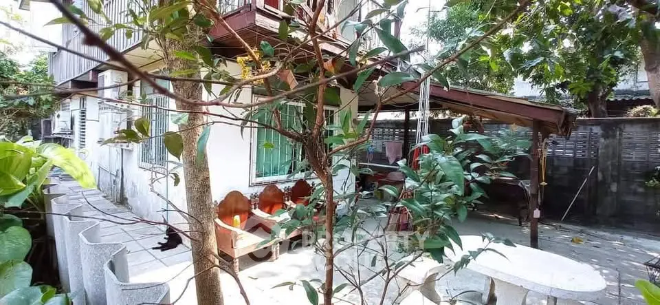 Charming outdoor area with seating and lush greenery in a cozy residential setting.