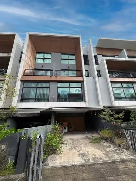 Modern multi-story townhouse with large windows and driveway in urban setting.