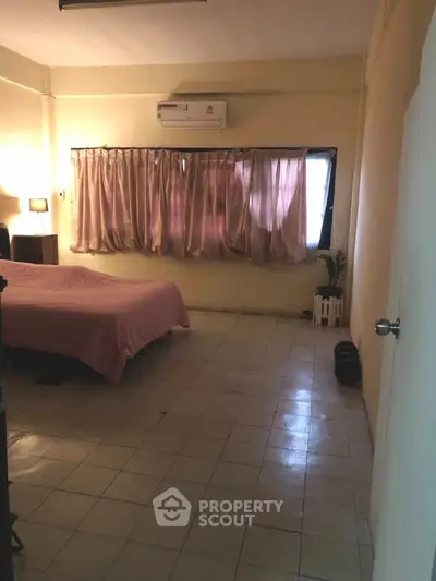 Cozy bedroom with tiled floor, air conditioning, and soft lighting for a comfortable living experience.