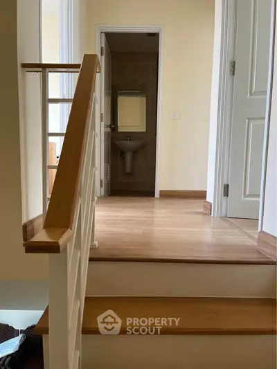 Charming interior hallway with wooden stairs leading to a cozy bathroom