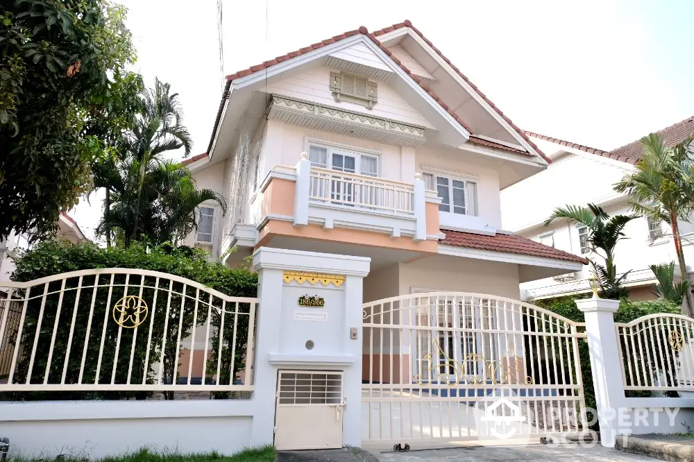 Elegant two-story residence with a classic design, featuring a grand entrance gate and lush greenery, nestled in a serene neighborhood.