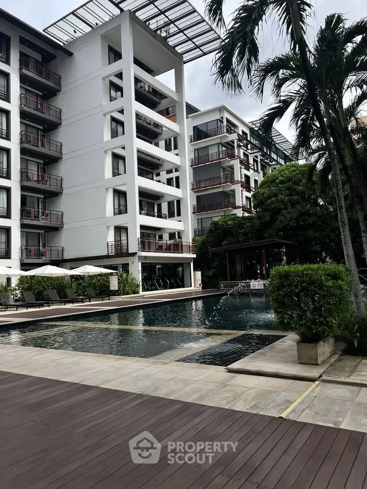 Luxurious modern apartment complex with pool and lush greenery, perfect for upscale living.