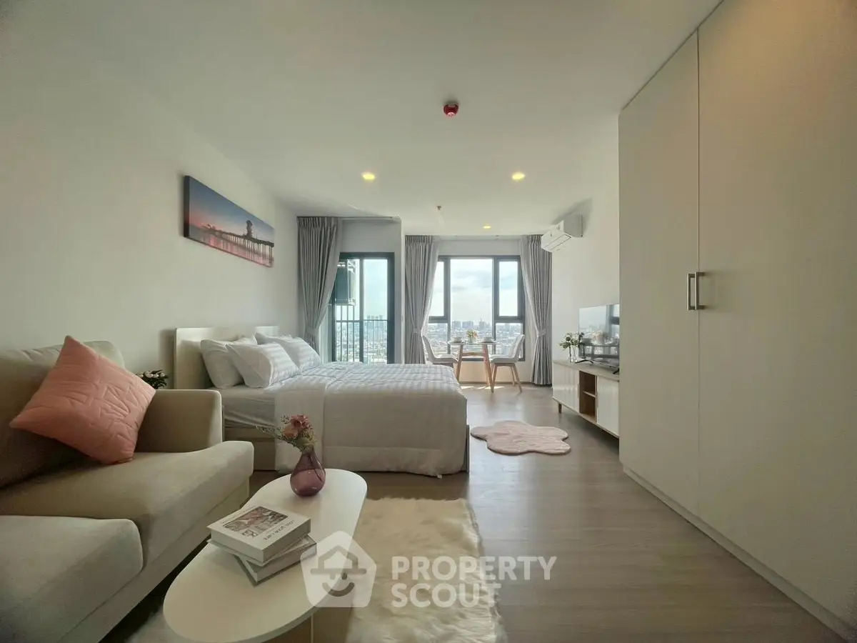 Modern studio apartment with cozy living area and stunning city view.