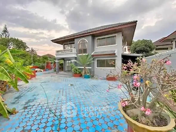 Charming two-story house with spacious garden and vibrant blue-tiled patio.