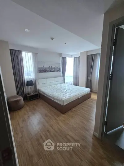 Spacious bedroom with modern decor and large windows offering natural light.