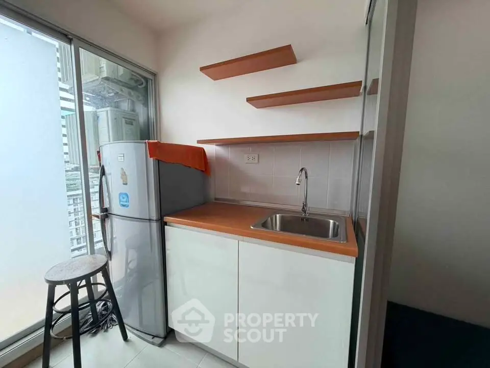 Modern kitchen with sleek design, featuring a compact fridge and stylish open shelves.