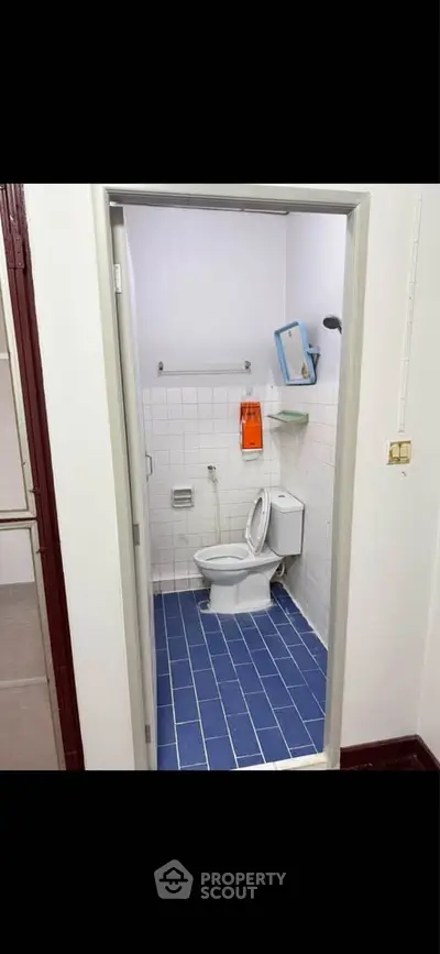 Compact bathroom with blue tiled floor and white fixtures, ideal for small spaces.