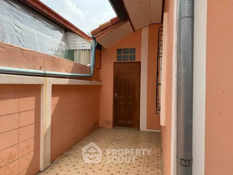 Charming exterior entrance with peach walls and tiled flooring, perfect for a cozy home.