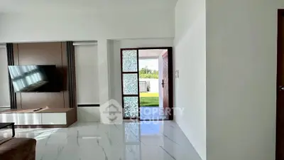 Modern living room with sleek TV setup and glass door leading to lush garden.