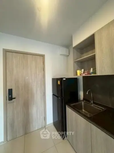 Modern kitchen with sleek cabinetry and compact refrigerator in a stylish apartment.