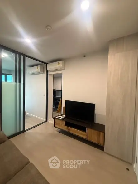 Modern living room with sleek design and glass partition, featuring a TV and air conditioning.