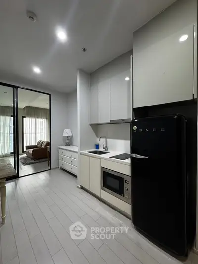 Modern kitchen with sleek appliances and open layout leading to cozy living room.
