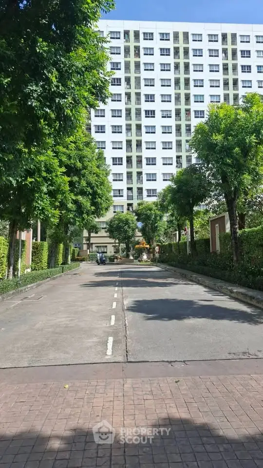 Modern residential building with lush greenery and spacious driveway entrance.