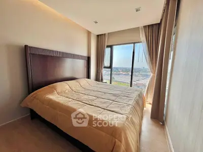 Spacious bedroom with large window offering stunning city views, perfect for relaxation and comfort.