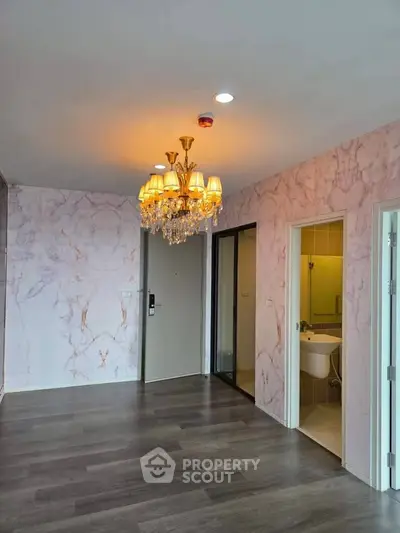 Elegant living room with chandelier and marble walls, featuring modern flooring.