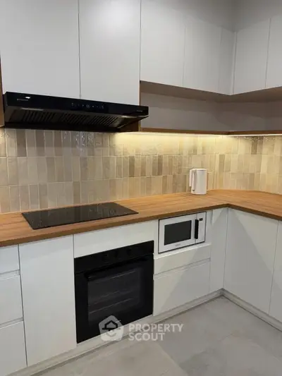Modern kitchen with sleek cabinetry, built-in oven, and stylish backsplash.