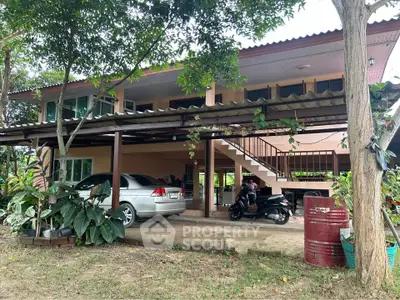 Charming two-story home with carport and lush greenery in tranquil setting.