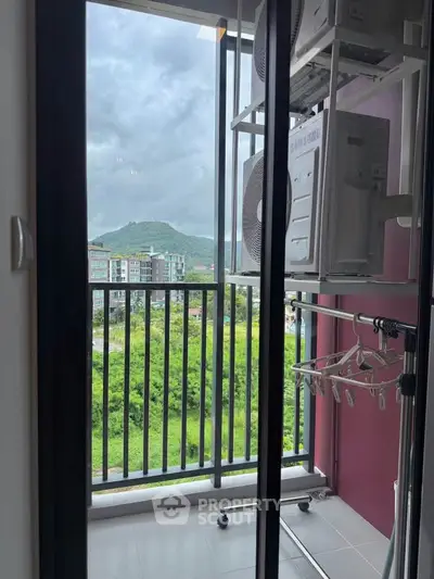 Charming balcony with scenic mountain view and laundry setup in modern apartment.