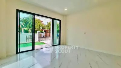 Spacious modern living room with large sliding glass doors opening to a lush garden view.