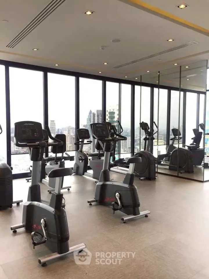 Modern gym with city view and exercise equipment in luxury building.