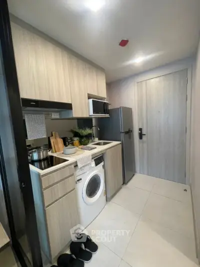Modern compact kitchen with integrated washing machine and sleek cabinetry