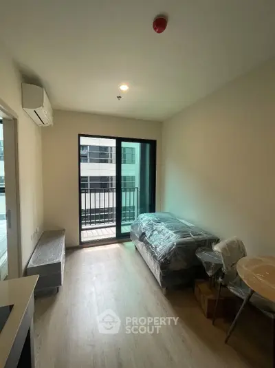 Modern living room with balcony access in a contemporary apartment, featuring sleek flooring and natural light.