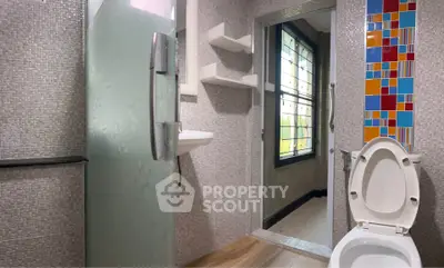 Modern bathroom with glass shower door and colorful tile accent wall