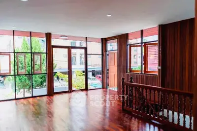 Spacious wooden interior with large windows and street view, perfect for modern living.