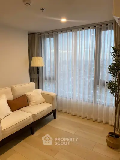 Elegant living room with large windows and cozy seating in a modern apartment.