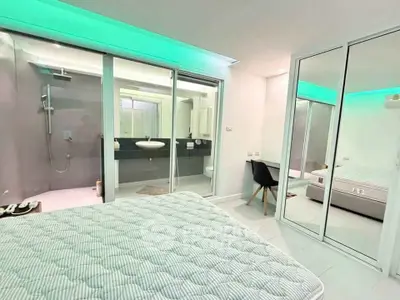 Modern bedroom with ensuite bathroom and mirrored closet doors, featuring sleek design and ambient lighting.
