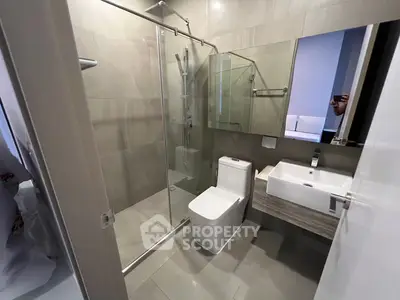 Modern bathroom with glass shower and sleek fixtures in contemporary apartment.