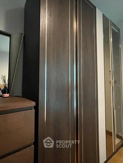 Modern bedroom with sleek wooden wardrobe and dresser, perfect for stylish storage solutions.