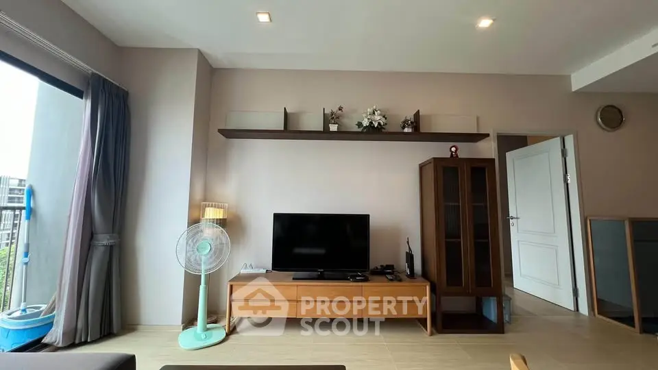 Modern living room with sleek TV stand, wall-mounted shelf, and stylish decor in a bright apartment.