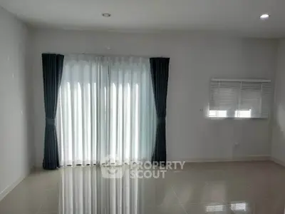 Spacious empty room with large windows and elegant curtains, perfect for customization.