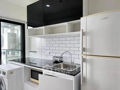 Modern kitchen with sleek black cabinets, white subway tiles, and essential appliances for stylish living.