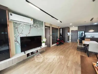 Spacious modern living room with stylish decor and open layout, featuring a large TV and elegant dining area.