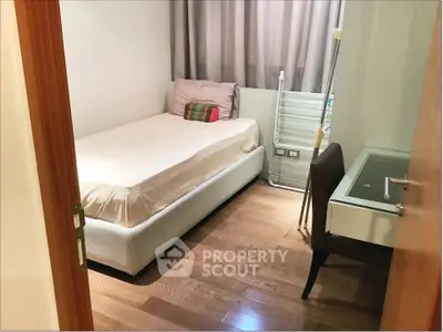 Cozy bedroom with wooden flooring and modern furniture in a stylish apartment.