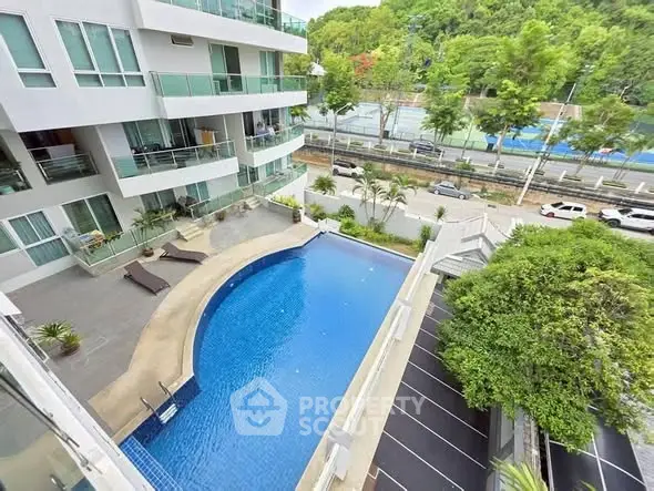 Stunning aerial view of modern apartment complex with pool and lush greenery.
