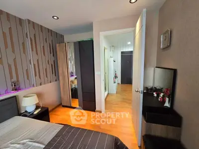 Modern bedroom with stylish decor and wooden flooring, featuring a cozy bed and sleek wardrobe.