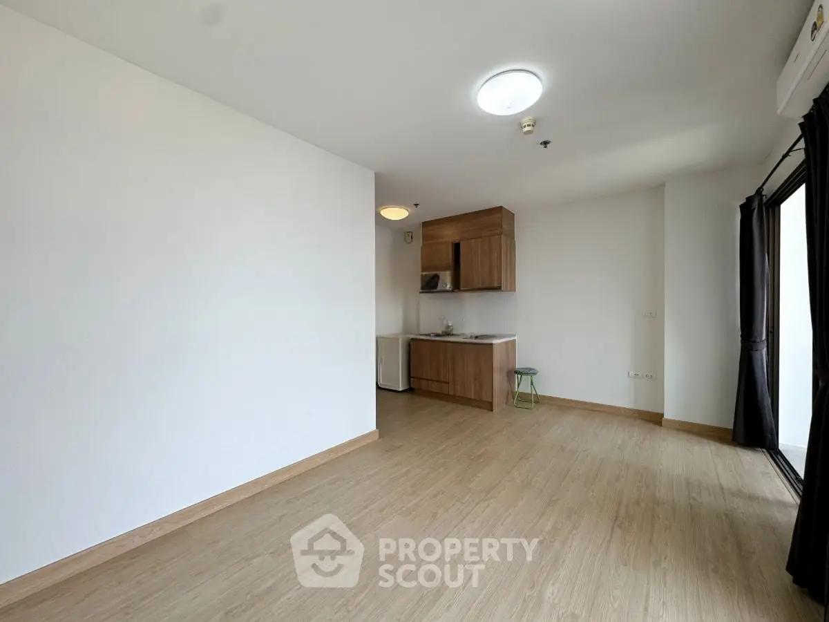 Spacious modern living area with wooden flooring and compact kitchen setup.