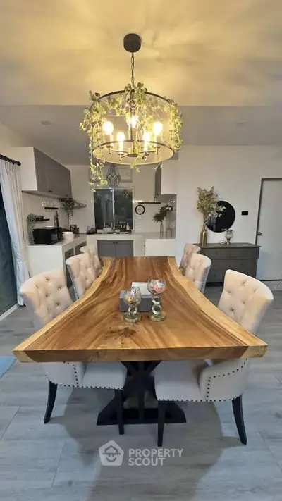 Elegant dining room with rustic wooden table and plush chairs under a stylish chandelier.