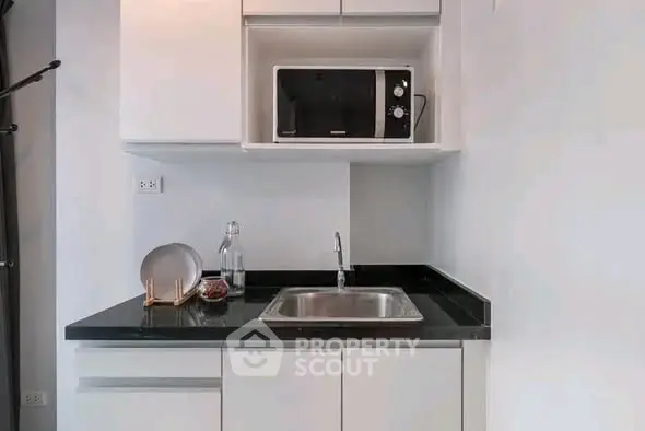 Modern compact kitchen with sleek cabinetry and built-in microwave