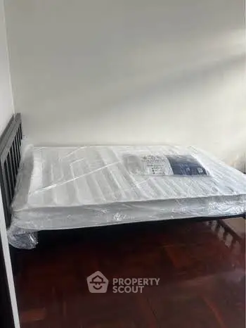 Brand new mattress on a wooden bed frame in a minimalist bedroom setting.
