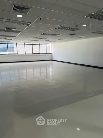 Spacious and well-lit commercial office space with reflective flooring and large windows offering ample natural light, ideal for a dynamic business environment.