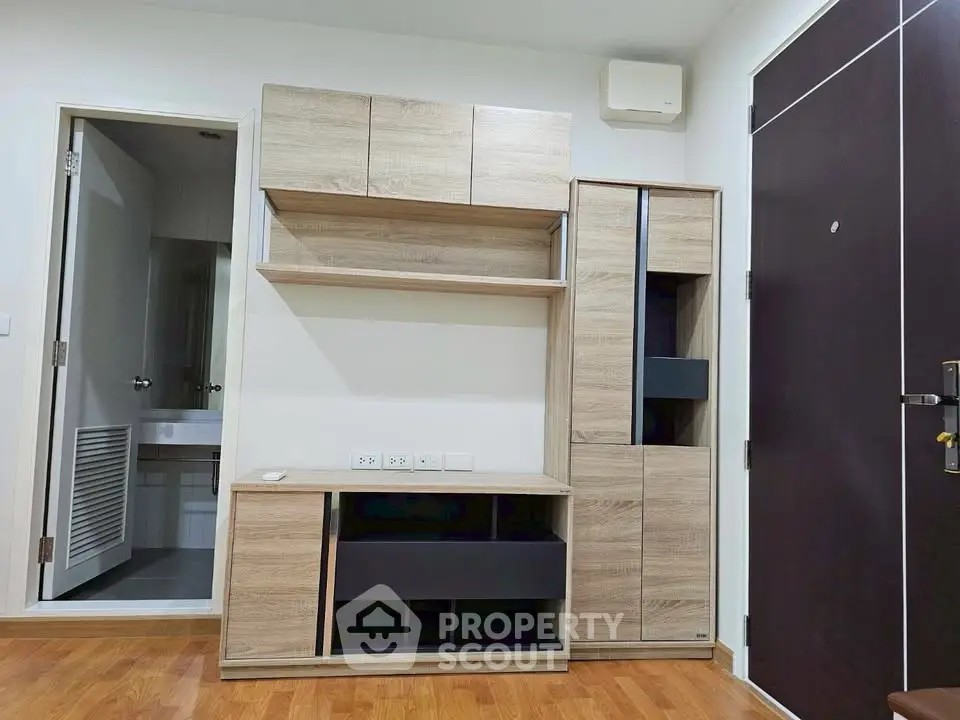 Modern apartment interior with wooden storage units and bathroom access, showcasing efficient space utilization.